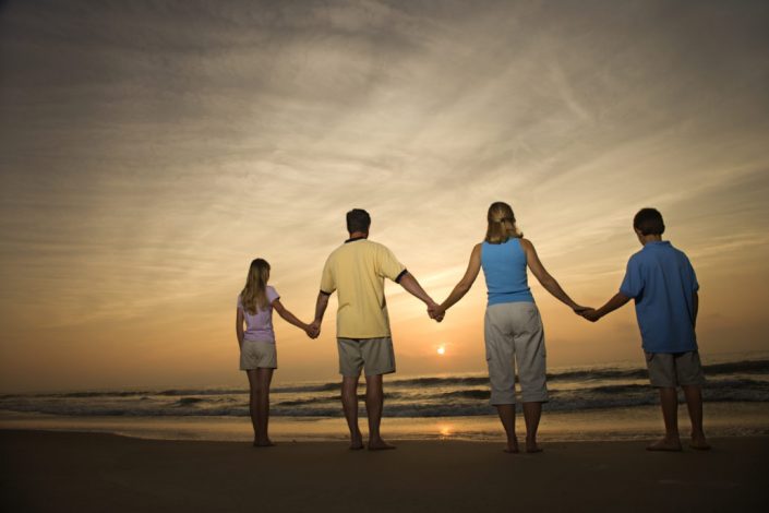Family holding hands on beach Is Your Family Over-scheduled?